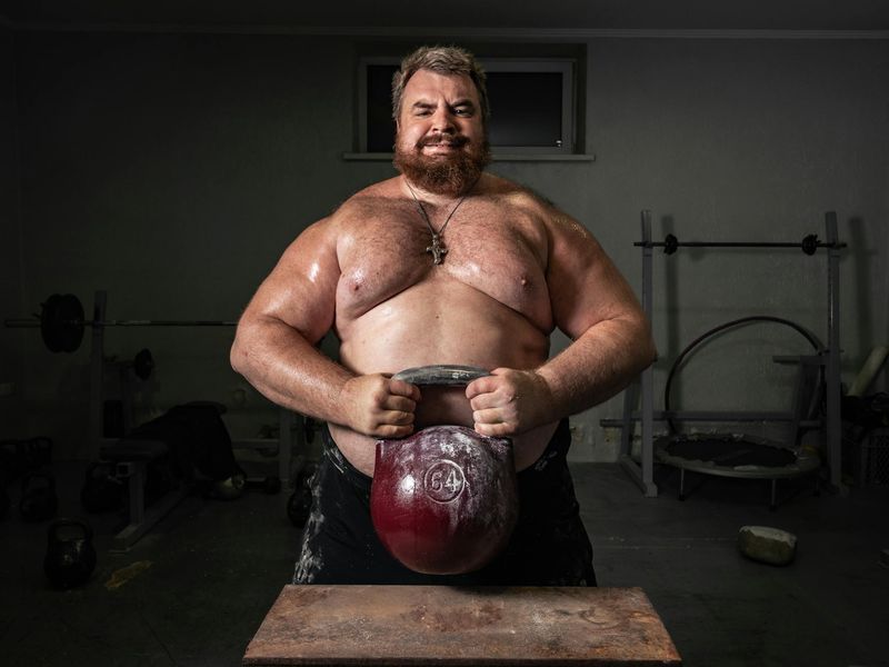 Strong man performing a controlled movement with heavy kettlebell